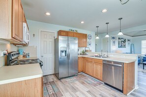 A modern kitchen with wooden cabinets, stainless steel appliances, and a central island. - Walk to Shore: Surfside Beach Home w/ Balcony! (Freeport)