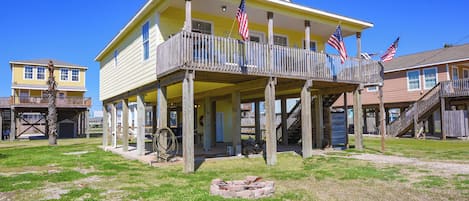 A two-story house with a balcony, a fire pit, and multiple American flags.