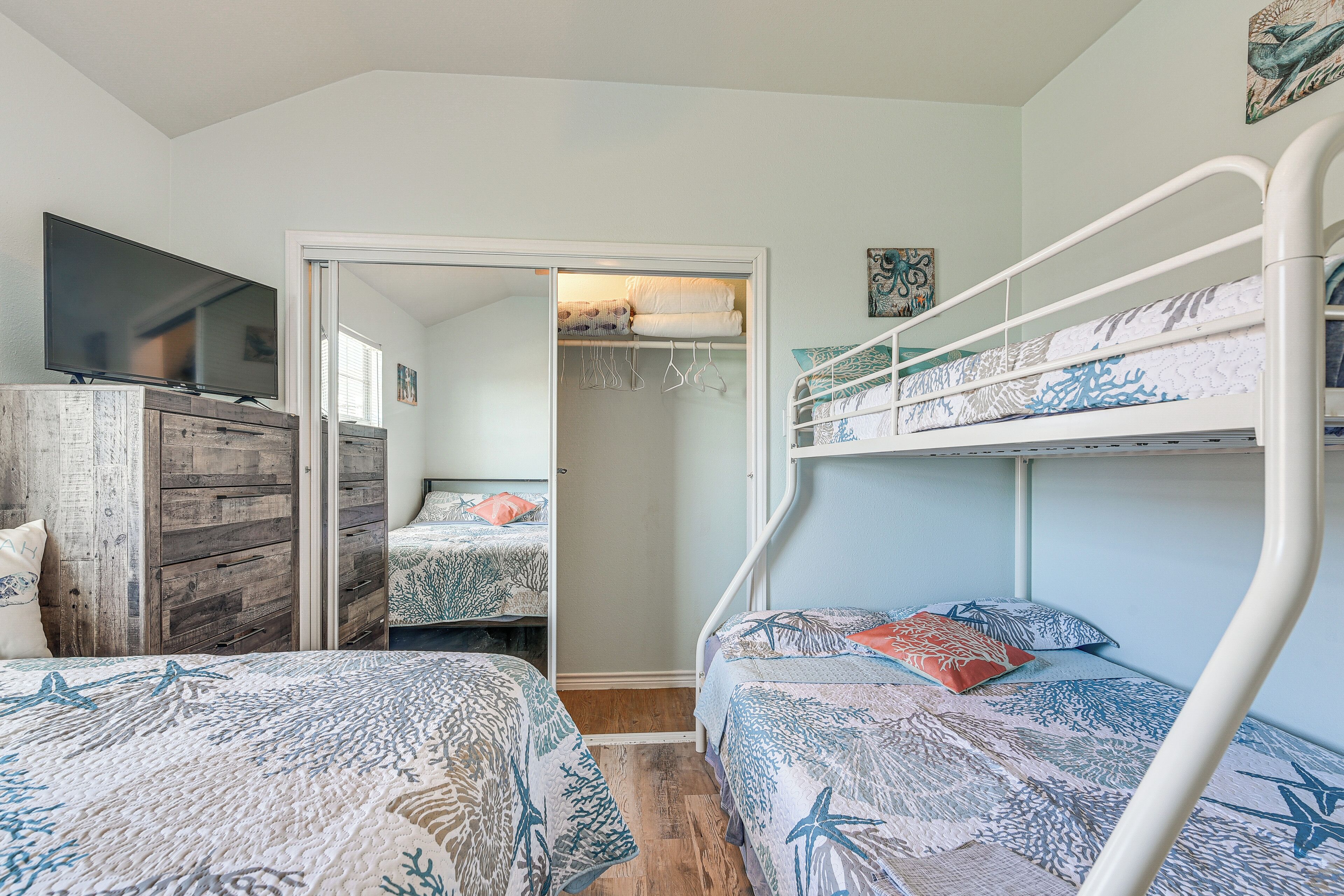 A bedroom with bunk beds, a TV on a wooden dresser, and a walk-in closet.
