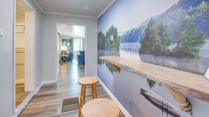 A hallway with a wooden bench, a mural of a lake, and a door leading to a closet.