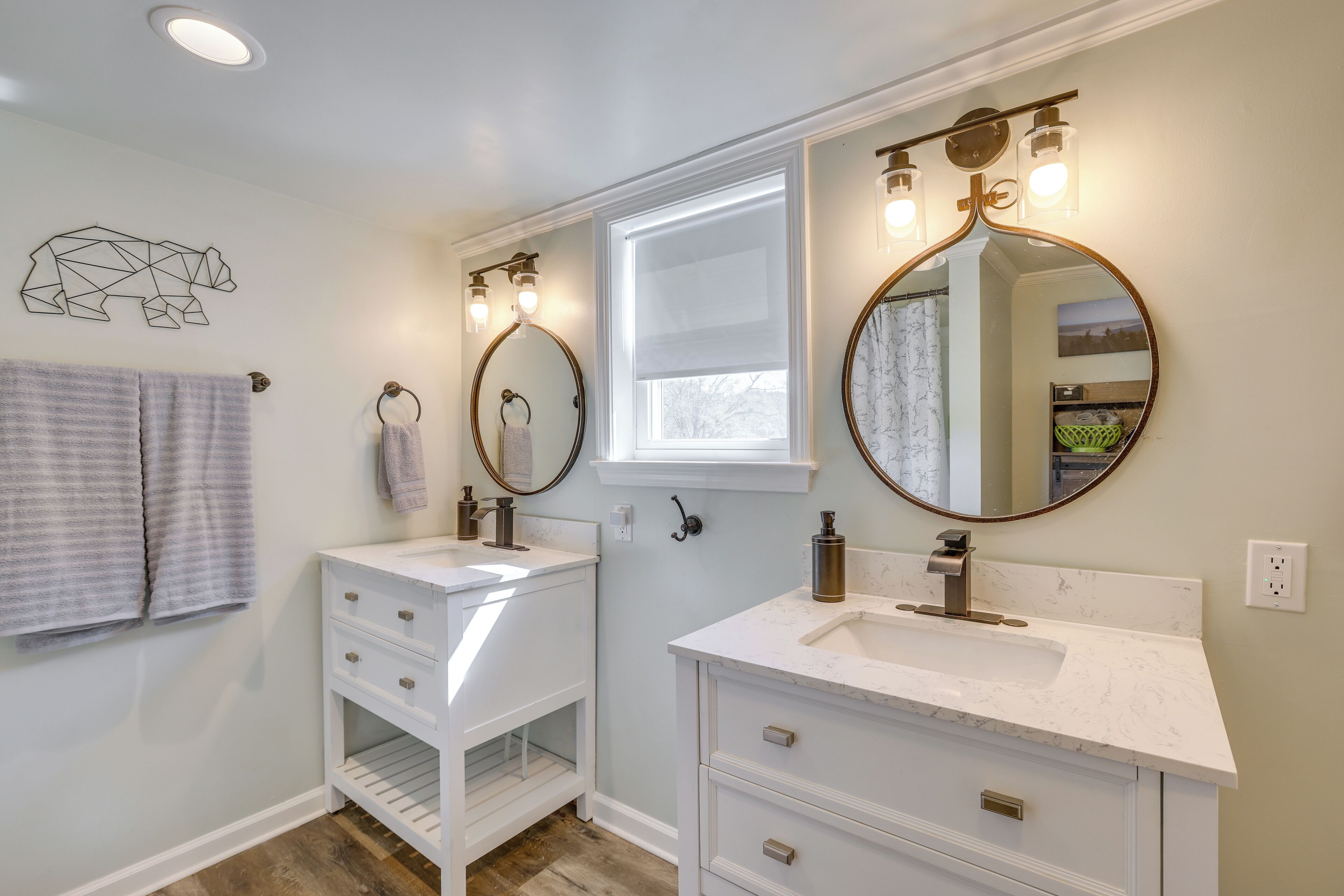 A bathroom with two sinks, a window, and a mirror with lights.
