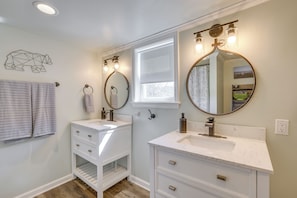 A bathroom with two sinks, a window, and a mirror with lights.