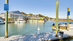 A marina with docked boats, a covered boat house, and a building with a sloped roof. - Idyllic Murrells Inlet Home < 1 Mi to Marsh Walk (Murrells Inlet)