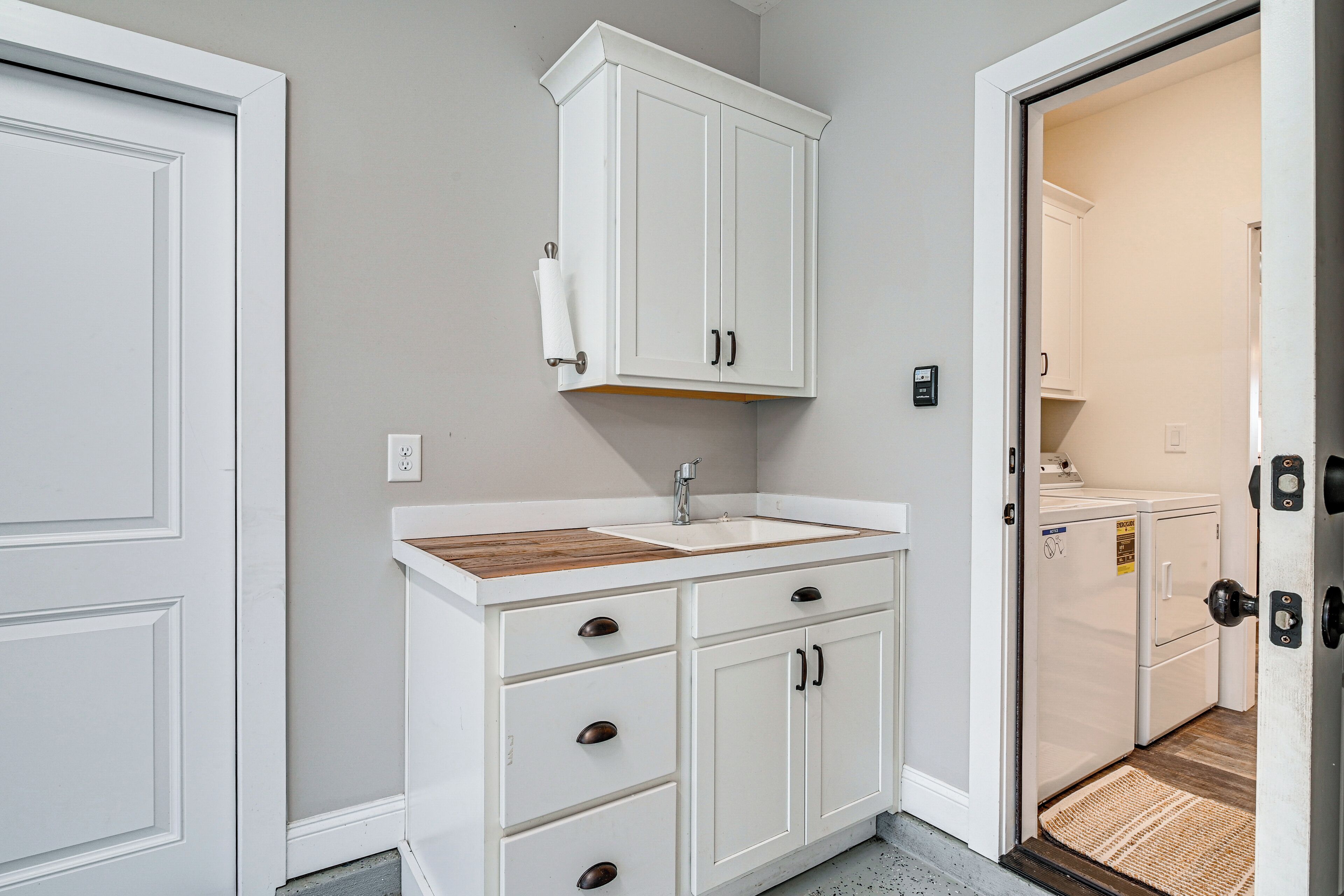 A bathroom with white cabinetry, a wooden countertop, and a sink.