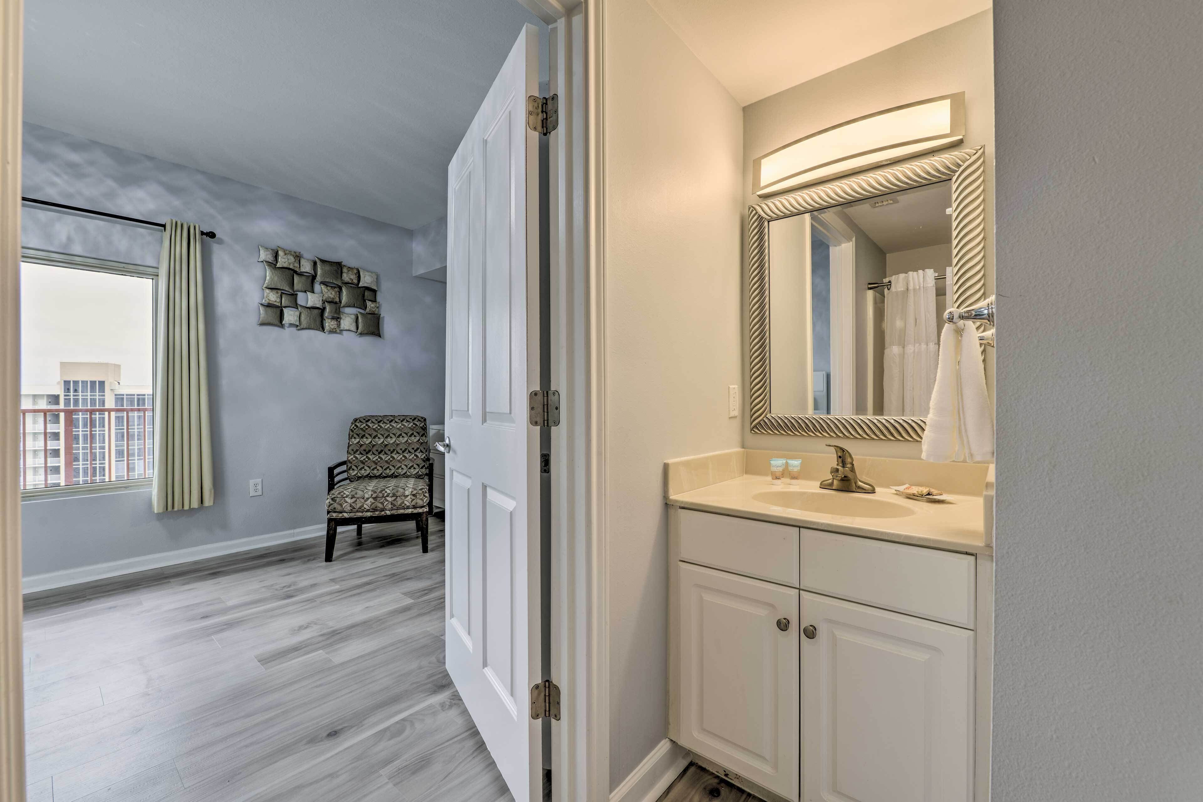 A bathroom with a large mirror, a sink, and a chair.