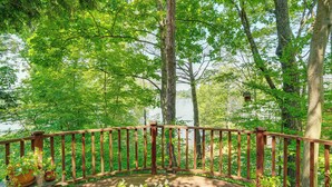 A wooden deck with potted plants, surrounded by trees and a lake view. - Treehouse Sanctuary Nature Retreat (Athens)