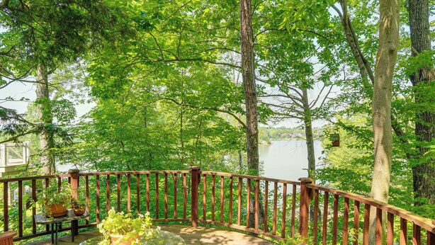 A wooden deck with a glass table and chairs, surrounded by a wooden railing, overlooking a lake. - Treehouse Sanctuary Nature Retreat (Athens)