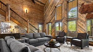 Un vaste espace de vie doté d’un intérieur en bois, d’un escalier et de grandes fenêtres offrant une vue sur l’extérieur.