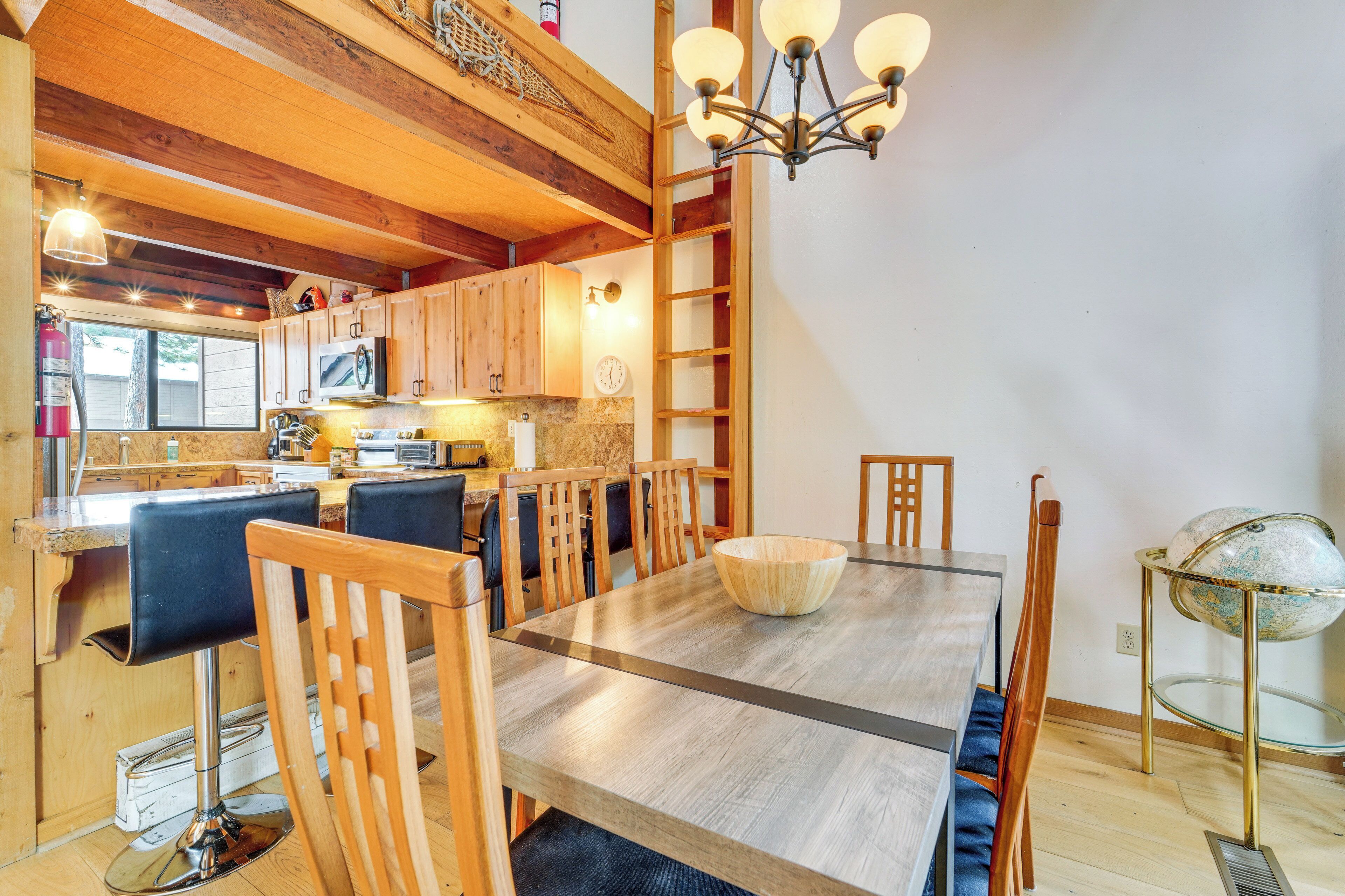 A spacious kitchen with wooden cabinets, a dining table with chairs, a chandelier, and a globe on a stand.