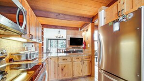 Une cuisine moderne avec des meubles en bois, des appareils électroménagers en acier inoxydable et un téléviseur intégré.