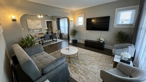 A modern living room with a gray sofa, a coffee table, and a TV mounted on the wall. - Spacious Retreat Near Convention Centers 4 Bedroom Home by RedAwning (Des Plaines)