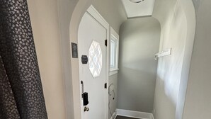 A narrow hallway with a wooden floor, white walls, and a white door with a window. - Spacious Retreat Near Convention Centers 4 Bedroom Home by RedAwning (Des Plaines)