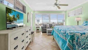 A bedroom with a bed, a TV on a dresser, a ceiling fan, and a window with blinds. - Las Hermanas 1 Studio by RedAwning (Longboat Key)