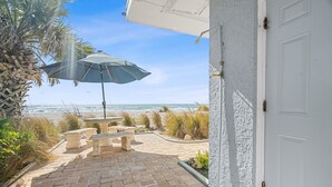 A patio with a table and chairs, a beach view, and a white door. - Las Hermanas 1 Studio by RedAwning (Longboat Key)