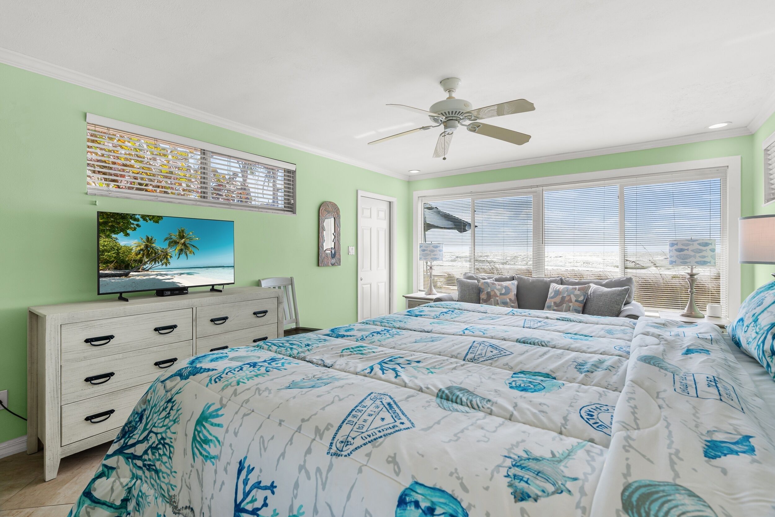 A bedroom with a bed, a dresser, a TV, and a ceiling fan.