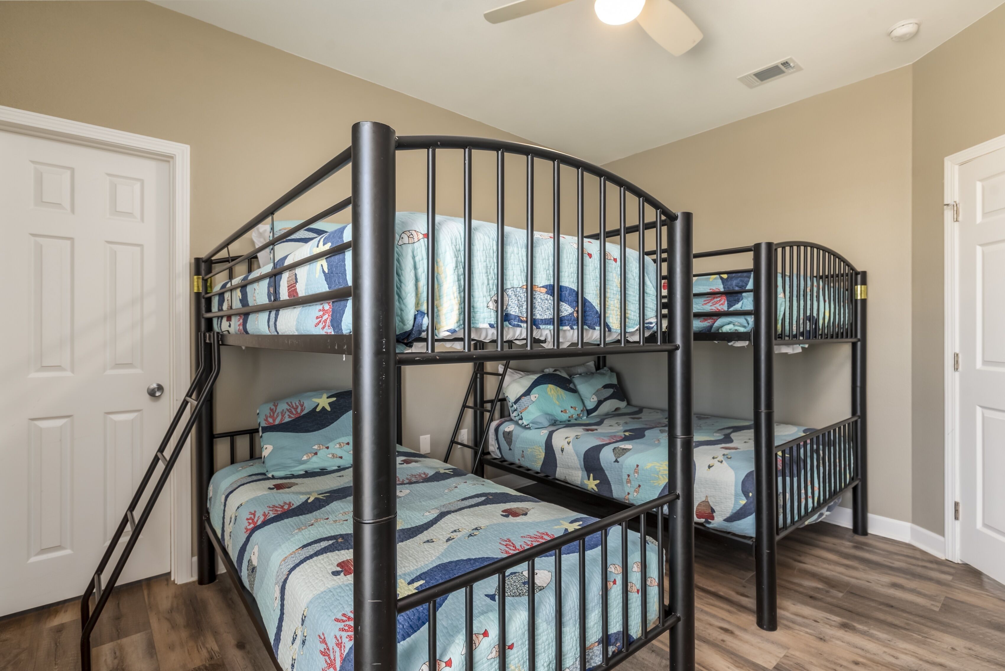 A bunk bed room with a curved metal frame, white doors, and a ceiling fan.