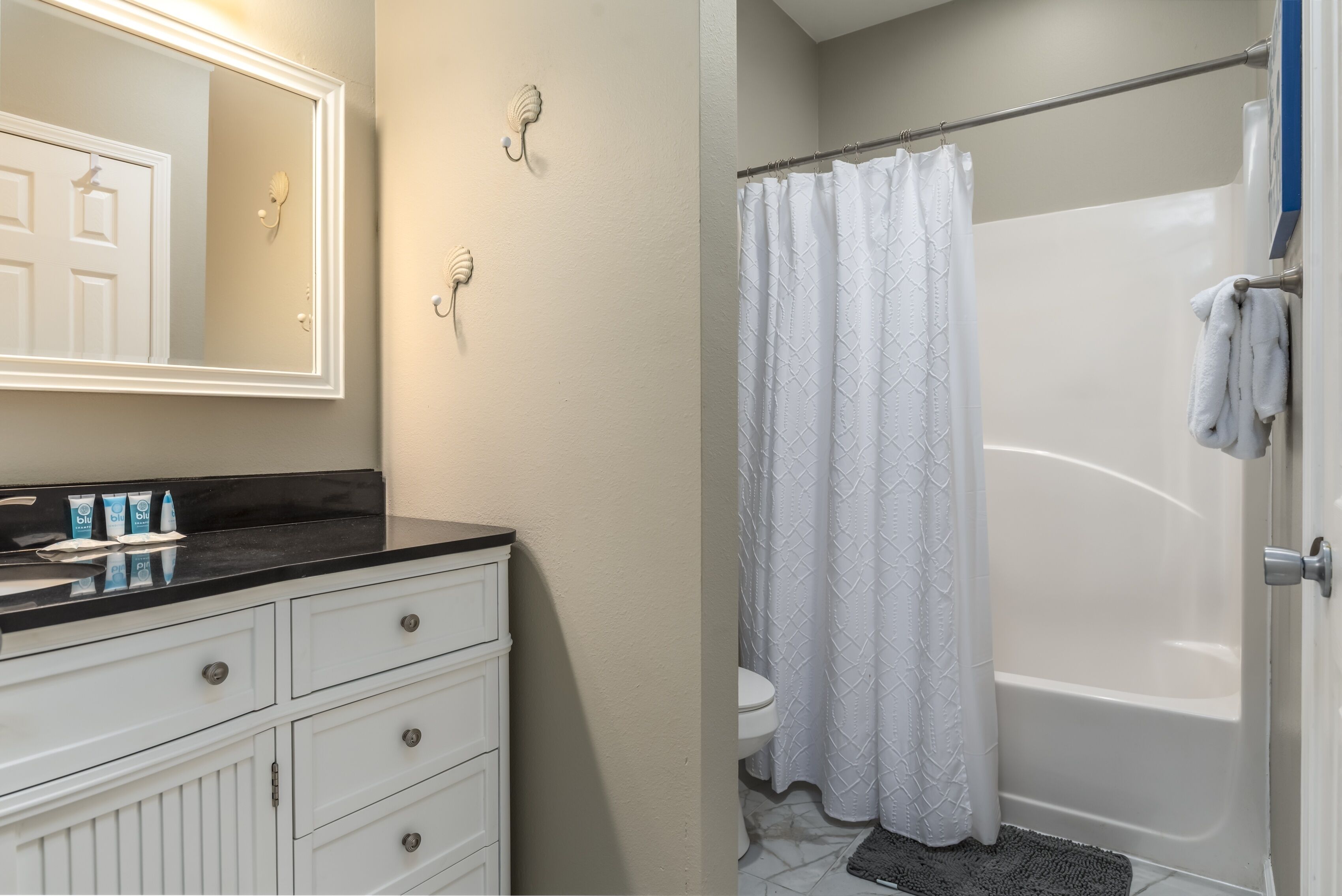 A bathroom with a white vanity, a mirror, and a shower curtain.