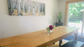 Ein Holzes Esstisch mit Blumen in einer Vase, einem Gemälde an der Wand und einer Topfpflanze.