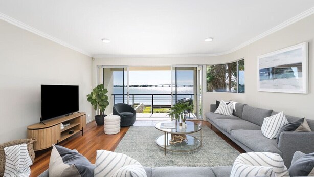 A modern living room with a flat-screen TV, grey sofas, a coffee table, and a view of the sea through large windows. - Panoramic views, 5-bedroom waterfront (Sylvania)