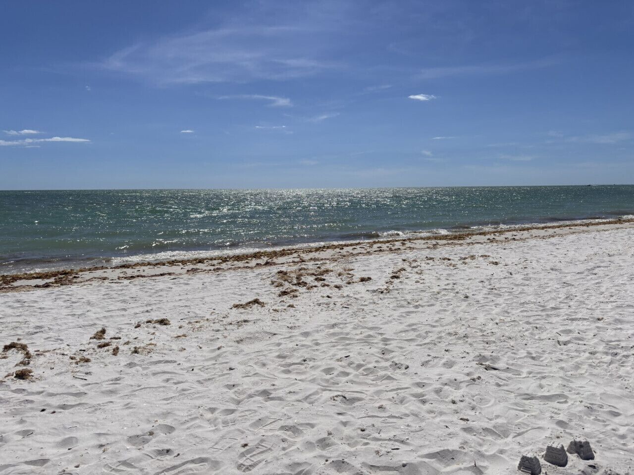 Una playa arenosa con huellas que conducen al agua.