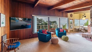 Una sala de estar moderna con paredes de madera, ventanas grandes y sillones azules.