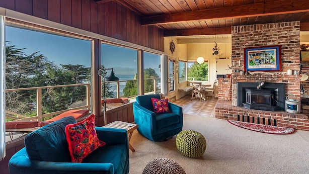 Una sala de estar acogedora con chimenea, ventanas amplias y vistas al exterior.