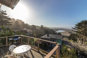 Una terraza con una mesa y sillas, con vista a un paisaje pintoresco de un río y colinas.