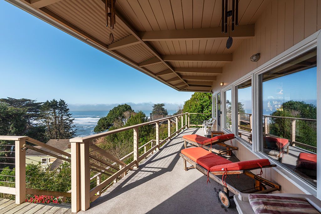 A wooden deck with lounge chairs overlooking a scenic ocean view.