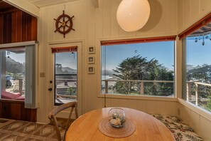 Un comedor acogedor con una mesa de madera, vistas despejadas al exterior y un timón de barco en la pared.