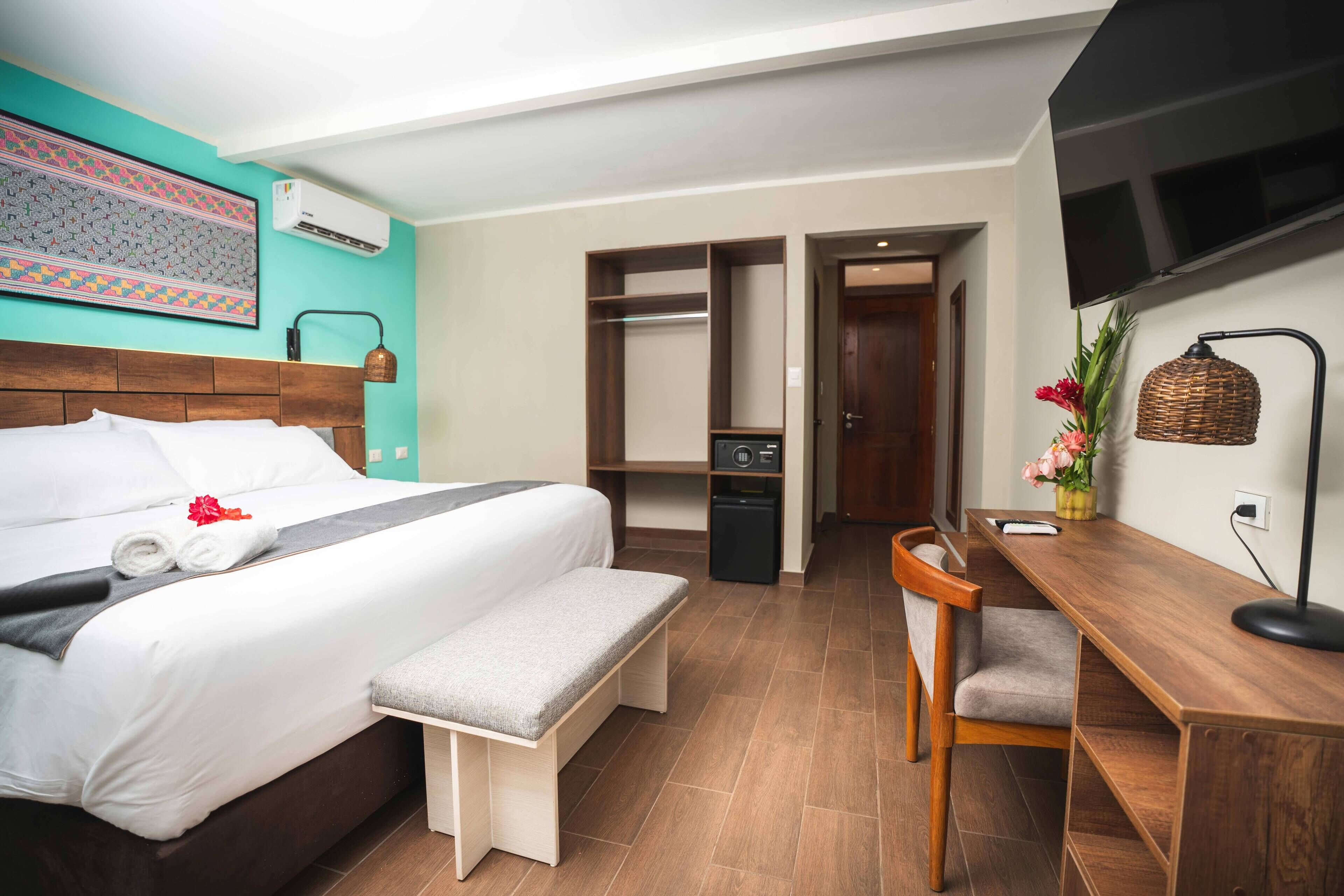 A hotel room with a bed, bedside table, desk, chair, and a wardrobe.
