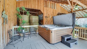 Een houten terras met een jacuzzi, hooibalen en een potplant.