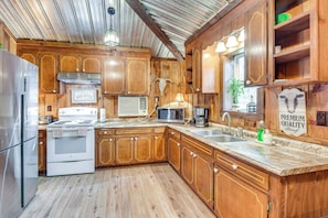 A kitchen with wooden cabinets, a stainless steel refrigerator, a stove, a microwave, and a sink. - Converted Barn Couple's Oasis Near Tallulah Gorge (Clarkesville)