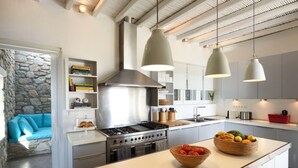 A modern kitchen with a central island, built-in oven, and pendant lighting. - Stunning 5-bed - Villa Big Blue (Mykonos)