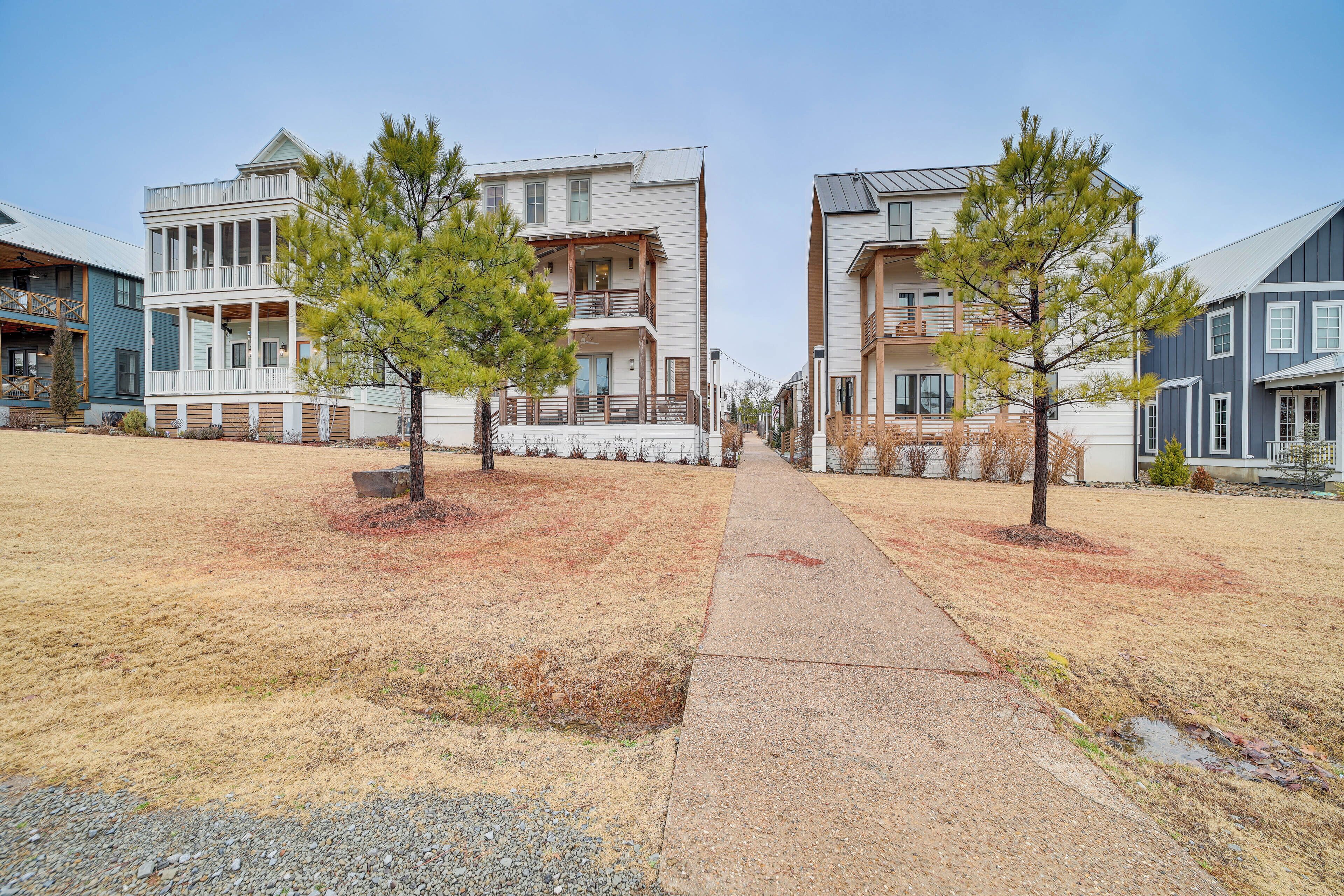A residential area with modern two-story houses, a paved walkway, and young pine trees.
