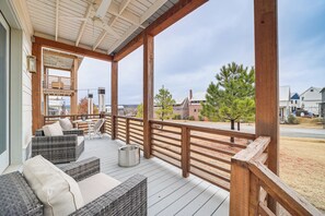 A covered outdoor deck with wicker furniture and a metal trash can. - Carlton Landing Home at Lake Eufaula! (Eufaula)