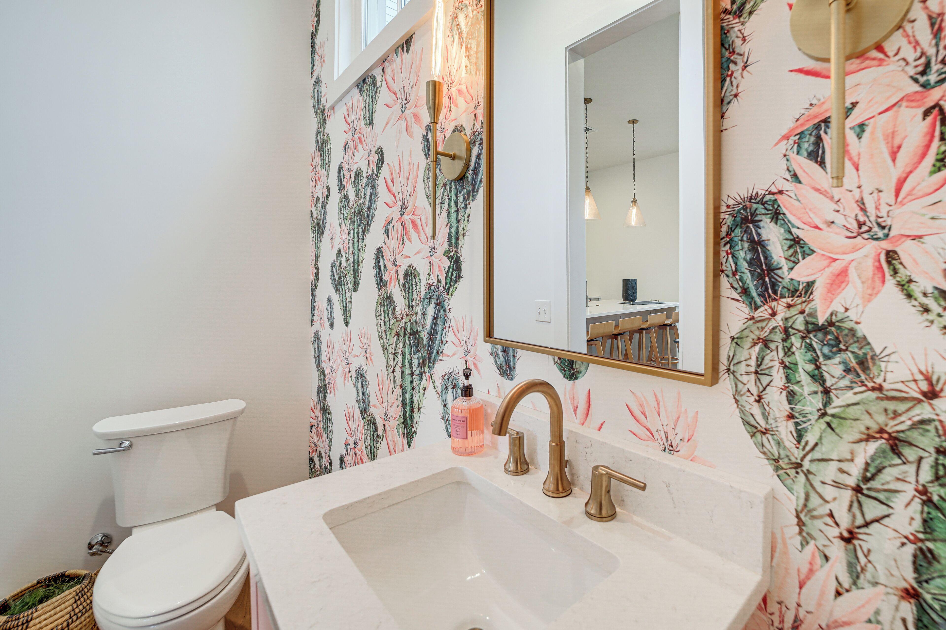A bathroom with a toilet, sink, and mirror. The walls are decorated with floral wallpaper.