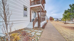 Une maison à deux étages dotée d’un balcon en bois et d’un chemin de pierre menant à la porte d’entrée.