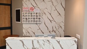 A reception desk with a marble-like design, wooden accents, and pendant lighting. - MondurO Hotel (Durrës)