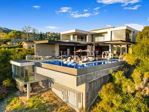 A modern house with a large swimming pool, outdoor seating, and a glass-enclosed structure. - Collingwood - Modern Architectural Home with Spectacular Views (Los Angeles)