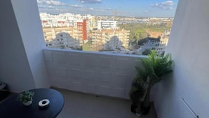 A balcony with a view of a cityscape, a small table with a plant, and a potted plant beside the balcony. - 1-bed - Sleeps 4 - Free Parking (Portimão)