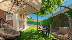 A backyard with a pool, outdoor seating, and a hanging chair.