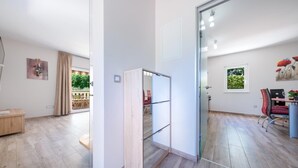 A modern interior with a glass partition, a dining area with red chairs, and a view of the outdoors.