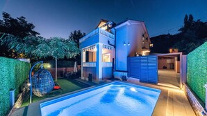 A modern house with a swimming pool, a covered patio, and a well-maintained garden.