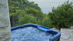 Un bain à remous avec vue sur la mer et les arbres.