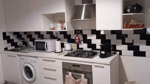 Une cuisine compacte équipée d’un lave-linge, d’un four à micro-ondes, d’un four traditionnel et d’une machine à café.