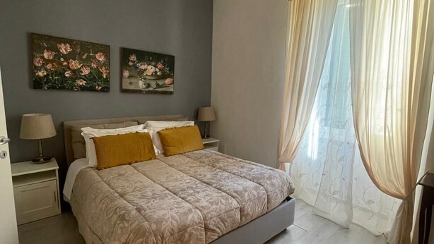Une chambre à coucher comprenant un lit, deux tableaux accrochés au mur, un lustre et un appareil de climatisation.