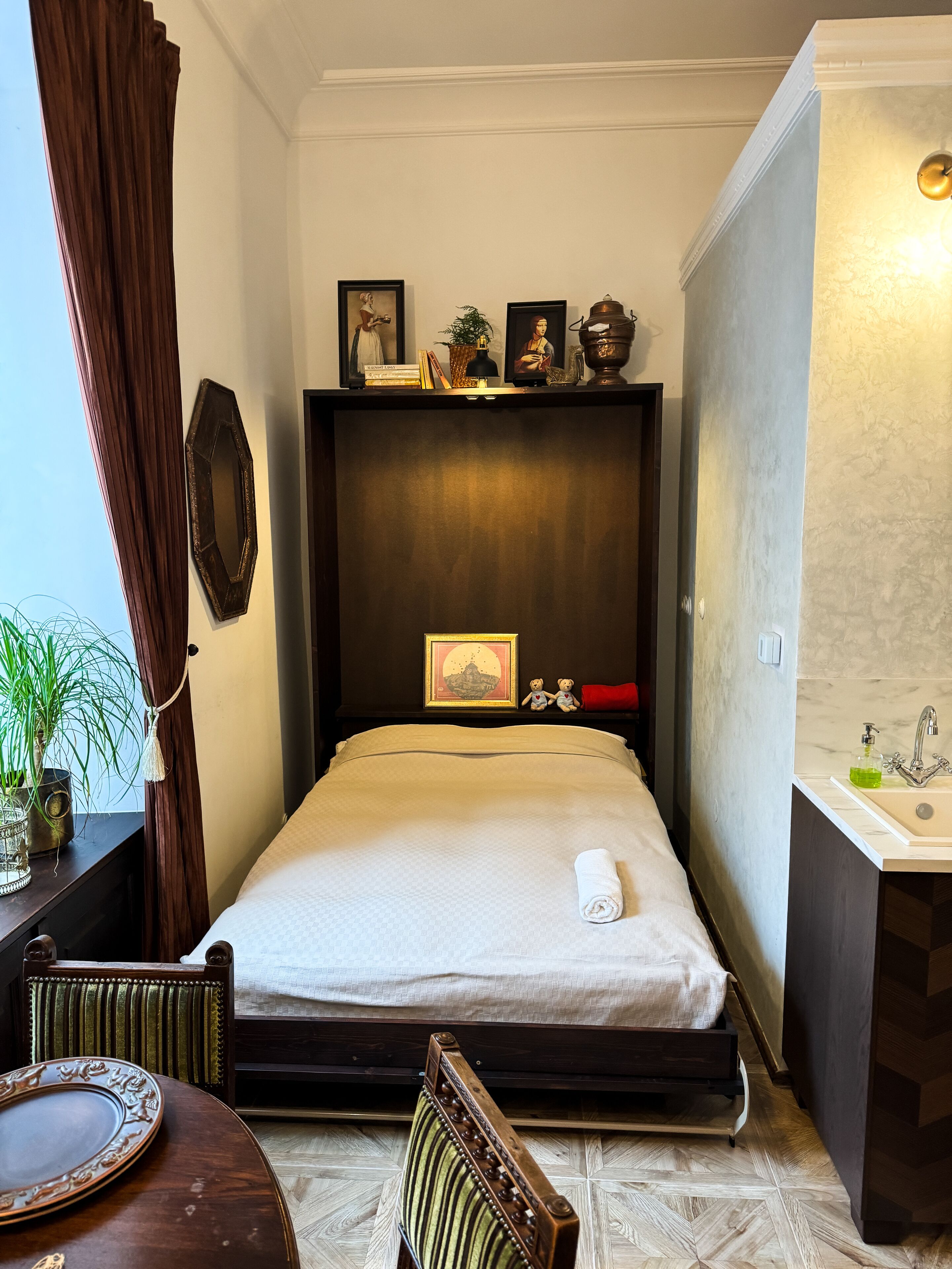 Une chambre d’hôtel de taille réduite, comprenant un lit, une table de chevet et un petit espace bureau.