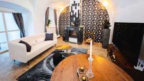 A modern living room with a sofa, a wooden coffee table, a fireplace, and a TV. - Opera apartments  (Banska Stiavnica)