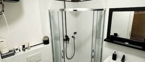 Une salle de bain moderne avec une douche à parois de verre, des toilettes blanches et un lavabo sur colonne.