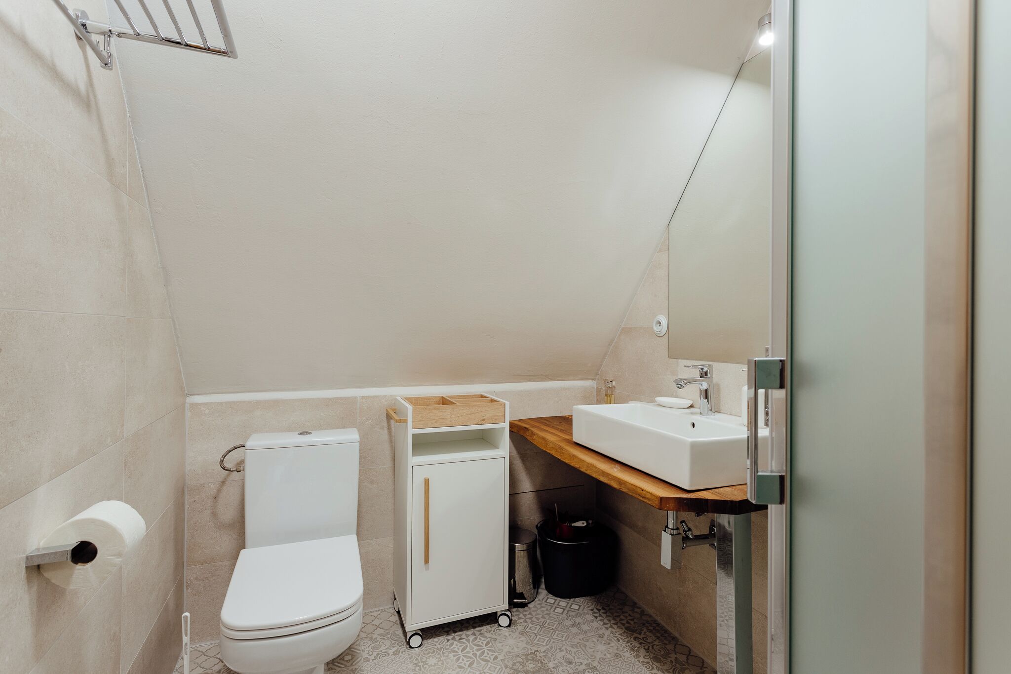 Un baño pequeño y moderno con inodoro, lavabo, armario y cubo de basura.